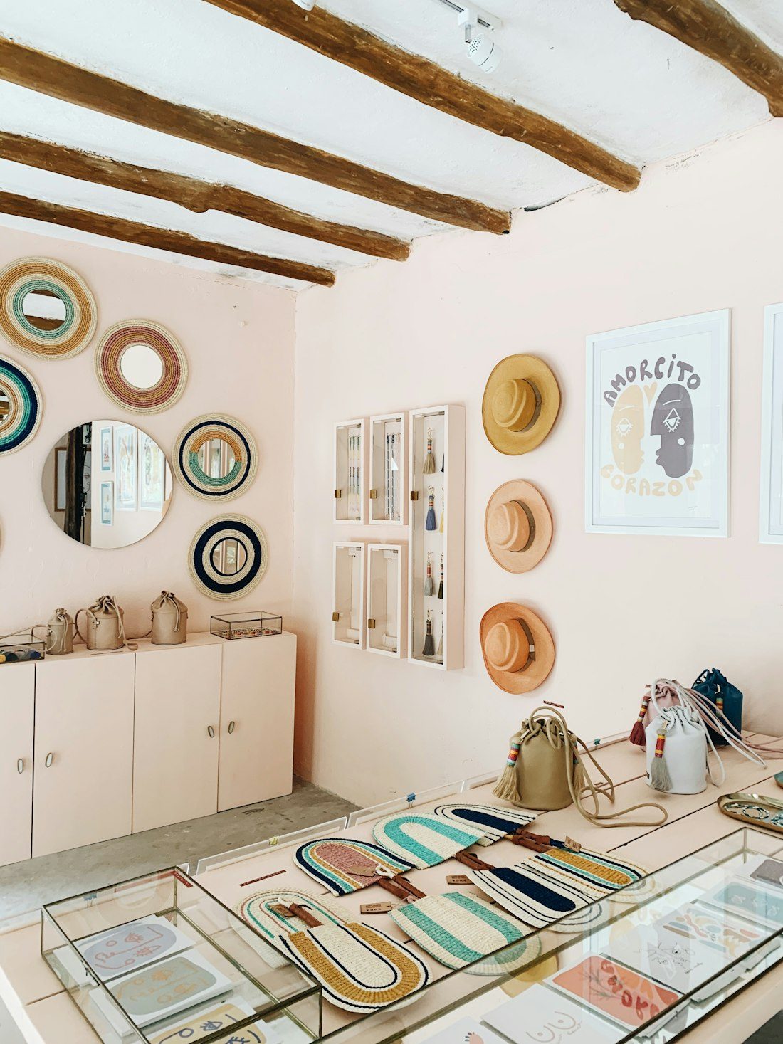Helle Boutique mit rosa Wand, Spiegeln, Hüten und Taschen (Beispielfoto)